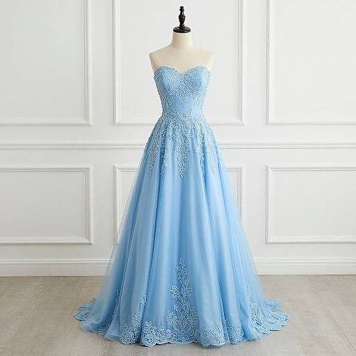 Photograph of a strapless, light blue, lace-embellished evening gown on a black mannequin, set against a white paneled