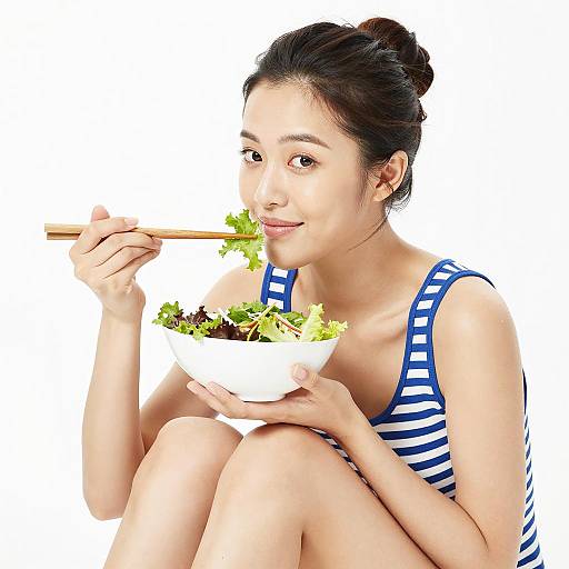 Asian Woman Eating Salad with Chopsticks