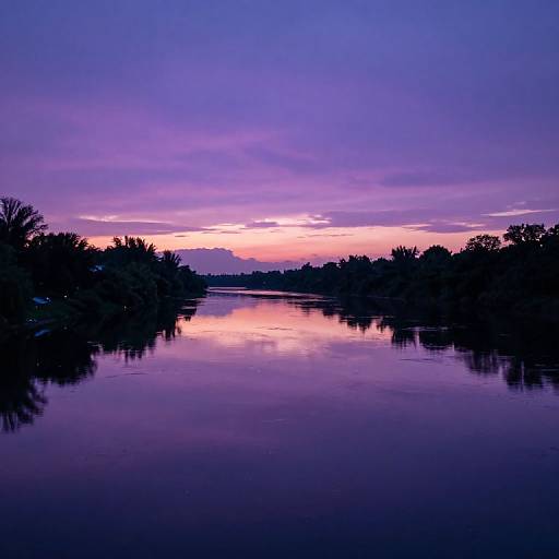 Photograph of a serene lake at sunset, featuring a vivid purple and pink sky, reflecting on calm water, with silhouetted trees on both