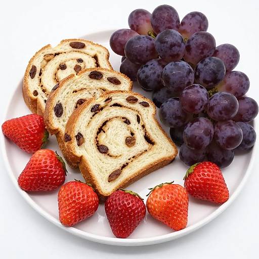 Photograph of sliced raisin bread, dark purple grapes, and red strawberries on a white plate, showcasing vibrant, fresh, colorful fruits and bread.