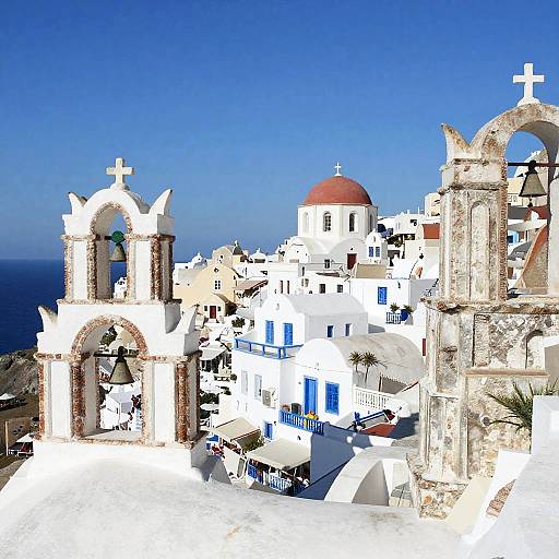 Photograph of a bright, sunlit Greek island town with white-washed buildings, blue doors, red dome, stone arches, and clear blue