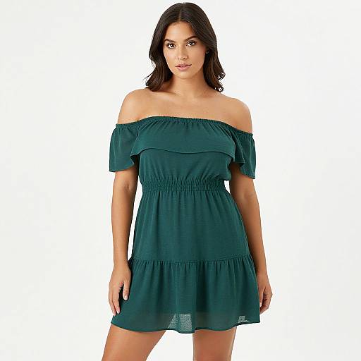 Photograph of a young woman with medium-length brown hair, wearing an off-shoulder, dark teal, short, ruffled dress, standing against