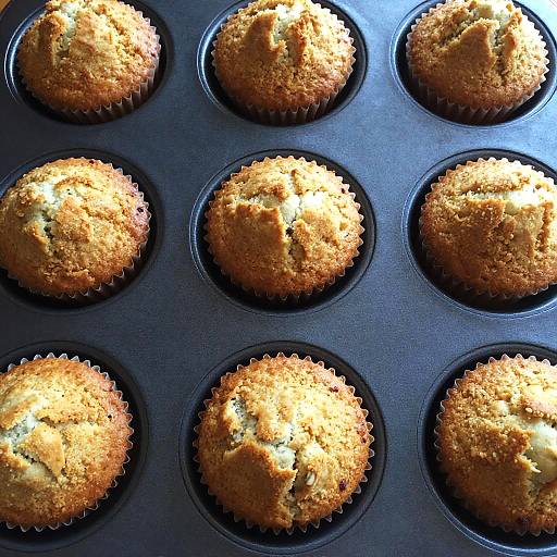 Photograph of nine golden-brown muffins in a black, circular silicone muffin tray, with a slightly textured, crumbly top.