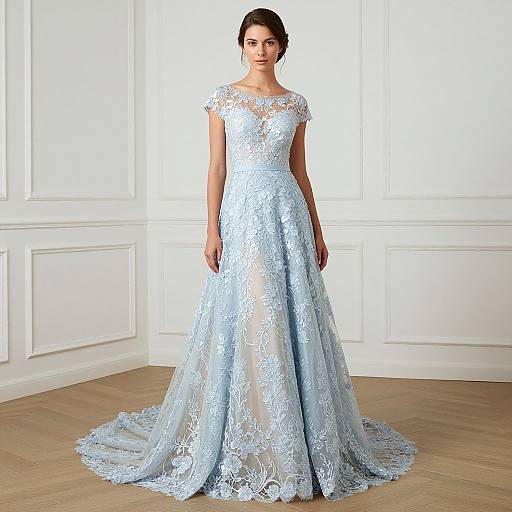 Photograph of a brunette woman in a light blue, lace, floor-length wedding gown with a sheer neckline, standing in a white-paneled room with