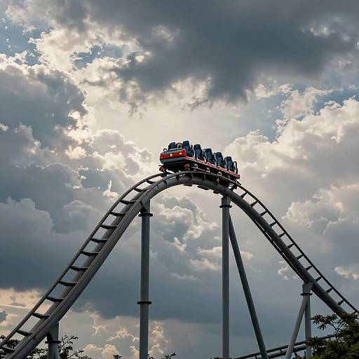Photograph of a roller coaster with a car full of passengers cresting a steep, arched track against a dramatic, cloudy sky.