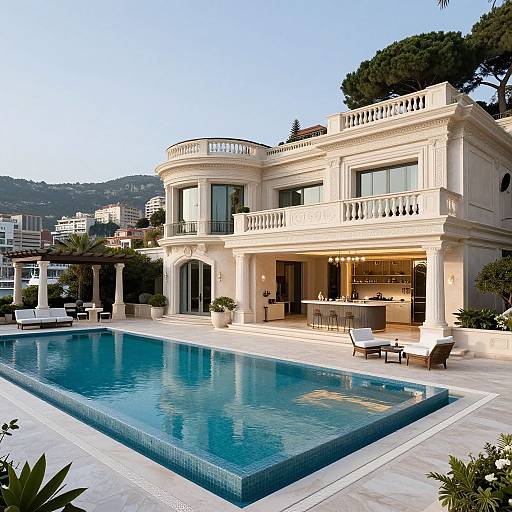 Photograph of a luxurious, two-story Mediterranean-style mansion with a large, rectangular pool, white balustrades, and mountainous backdrop at dusk.