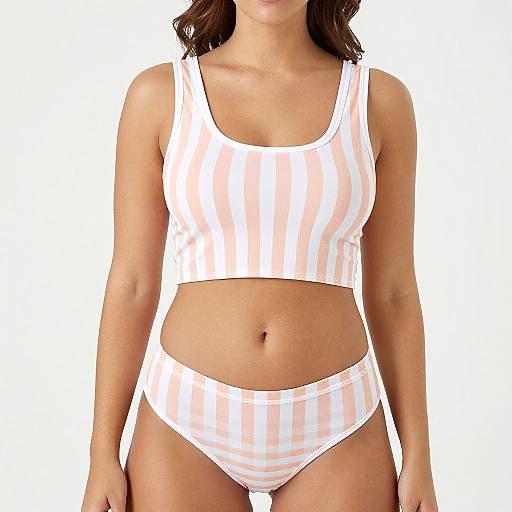Photograph of a woman wearing a white and pink vertical striped crop top and high-waisted bikini bottoms, with a plain white background.