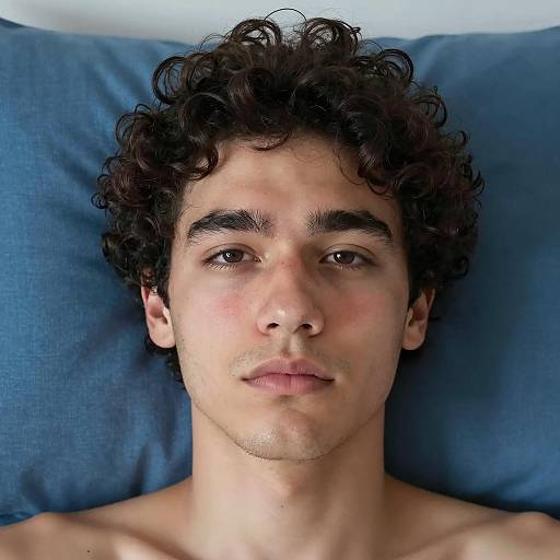 Young Man with Curly Hair Lying on Blue Pillow