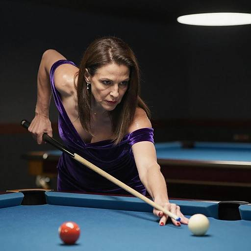 Photograph of a focused, brunette woman in a purple dress, aiming a pool cue at a white ball on a blue-felt pool table.
