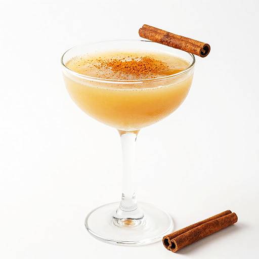 Photograph of a glass bowl filled with orange-colored cocktail, dusted with cinnamon, with two cinnamon sticks—one on top, one below.
