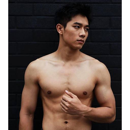 Shirtless Muscular Asian Man Against Dark Brick Wall