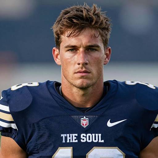 Photograph of a focused, young white male football player with short brown hair, wearing a navy blue 