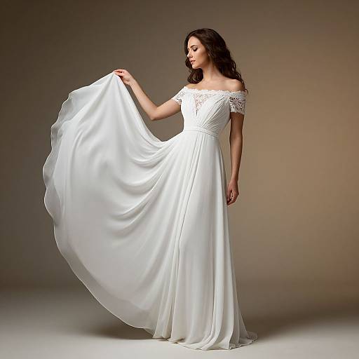 Photograph of a woman in a white, off-the-shoulder, lace-trimmed wedding dress, holding the flowing skirt, standing against a