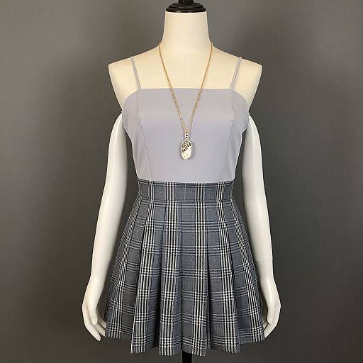 Photograph of a white mannequin wearing a light gray, strapless top with a high-waisted, black-and-white plaid skirt,