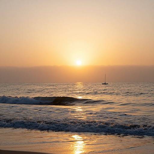 Photograph of a serene sunset over a calm ocean, with gentle waves, a small sailboat in the distance, and a glowing orange sky reflecting on
