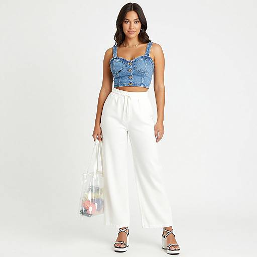 Photograph of a confident woman with medium skin tone, black wavy hair, wearing a blue denim crop top, white high-waisted skirt,