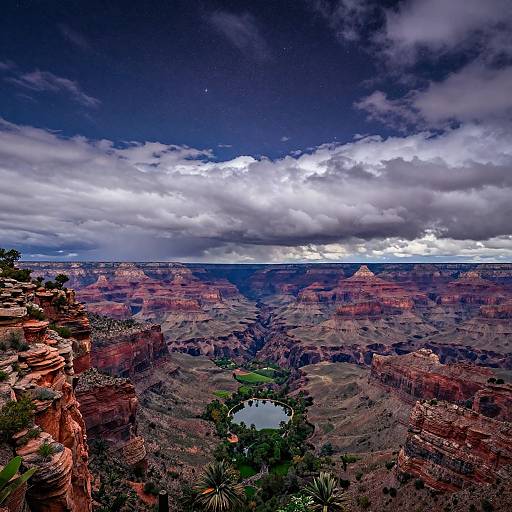 Photograph of Grand Canyon at sunset with dramatic clouds, vibrant red and orange rock layers, small green oasis in the center.