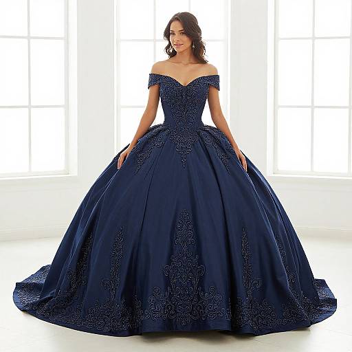 Photograph of a brunette woman in an off-shoulder, navy blue, intricately embroidered ball gown with a full skirt, standing in front of