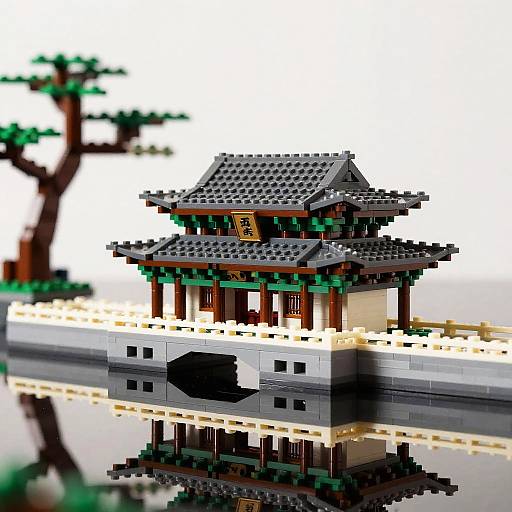 Photograph of a detailed LEGO model of a traditional East Asian pagoda with a black, tiled roof, reflected in a calm water surface, with a
