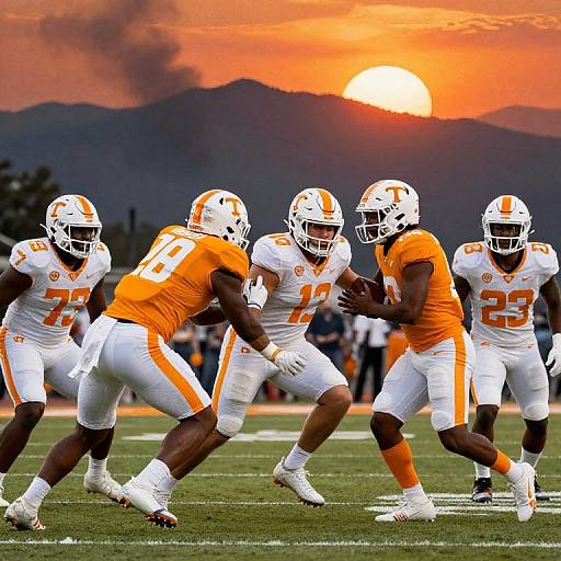 Photograph of five Tennessee Volunteers football players in white and orange uniforms running with the ball during a sunset game, mountains in the background.