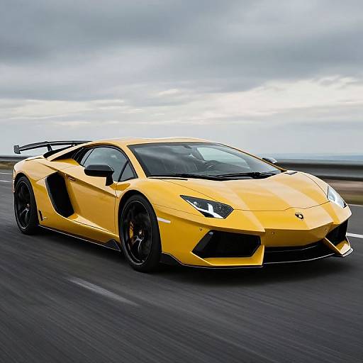 Photograph of a sleek, bright yellow Lamborghini Aventador with black accents, racing on a gray road under a cloudy sky.
