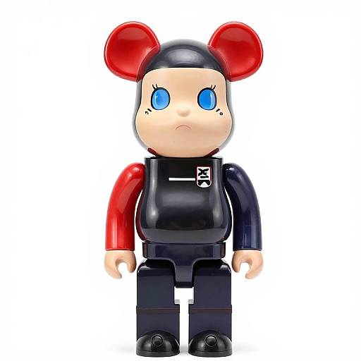 Photograph of a LEGO minifigure with blue eyes, red and black outfit, black cap with red mouse ears, and a serious expression.