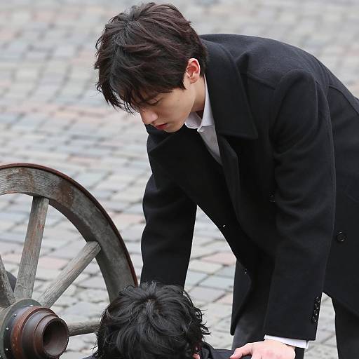 Man in Black Coat Leaning Over Another Person