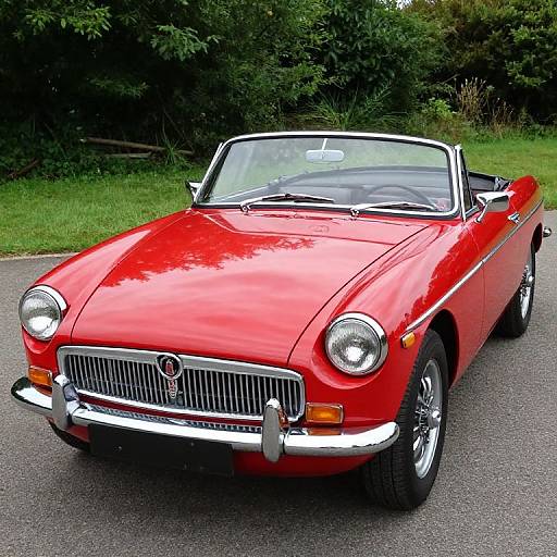 Photograph of a shiny red classic convertible car with chrome accents, parked on a paved road, surrounded by lush green trees.