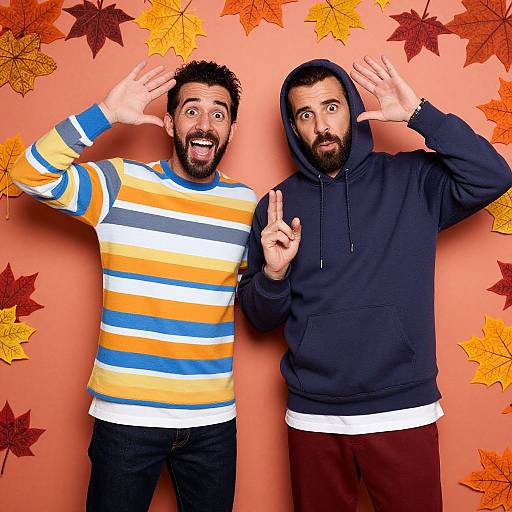 Photograph of two bearded men, one in a striped sweater and the other in a black hoodie, both making surprised expressions with hands on heads,