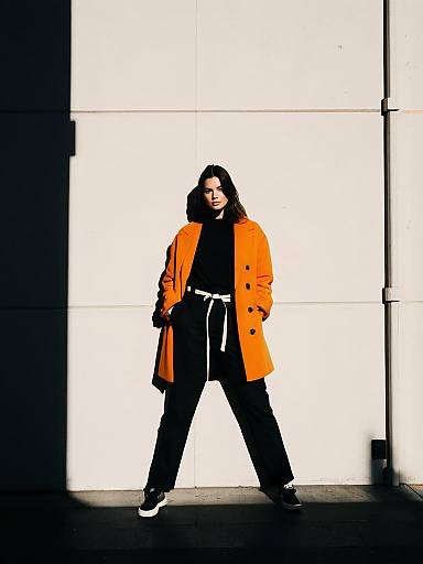 Woman in Orange Coat Against White Wall