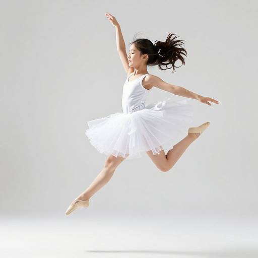 Photograph of an Asian female ballet dancer in a white tutu, leaping with arms and legs gracefully extended against a bright white background.