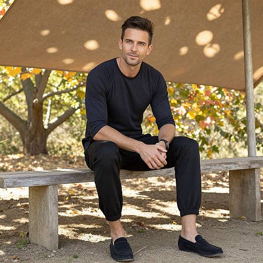 Photograph of a handsome, muscular man with short brown hair, light stubble, wearing a black long-sleeve shirt, black pants, and