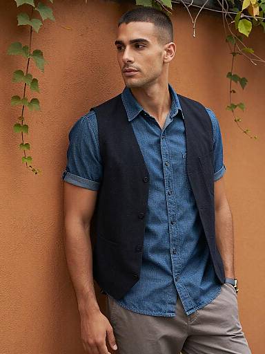 Man in Denim Shirt and Vest Against Orange Wall