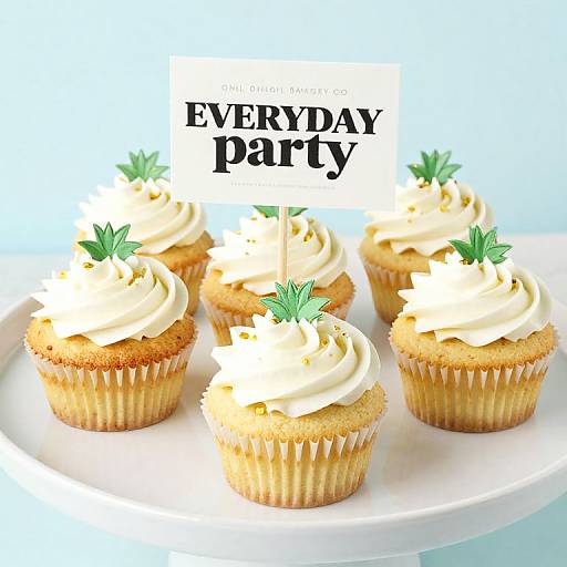 Photograph of five vanilla cupcakes with white swirl frosting, green sprig toppers, and 