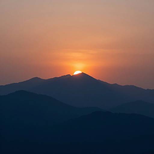 Photograph of a vibrant sunset over a mountain range, with the sun partially visible on a dark, silhouetted peak, casting an orange and