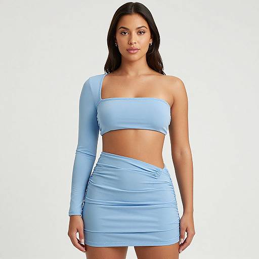 Photograph of a woman with medium brown skin and long black hair, wearing a light blue, one-shoulder, long-sleeve crop top