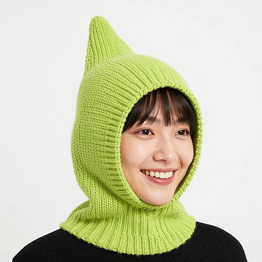 Photograph of a smiling Asian woman with dark hair, wearing a bright green, knitted cat-eared hat against a white background.