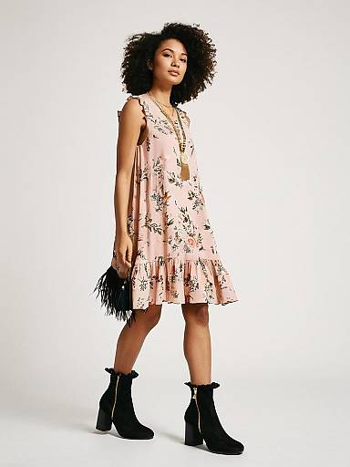 Woman in pink floral boho dress and black boots