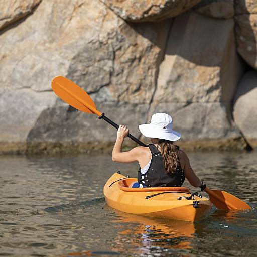 Woman Kayaking with Orange Paddle in Calm Water