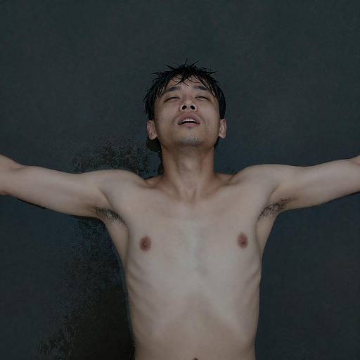 Shirtless man lying on wet dark surface