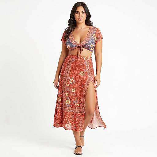 Photograph of a curvy woman with long black hair, wearing a floral red crop top and matching high-waisted skirt with a thigh-high slit