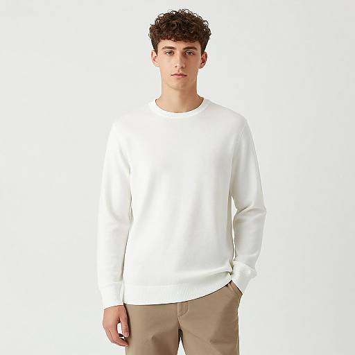 Photograph of a young man with curly brown hair, wearing a plain white long-sleeve shirt and beige pants, standing against a white background.