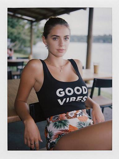 Photograph of a young woman with light brown skin and dark hair in a bun, wearing a black 