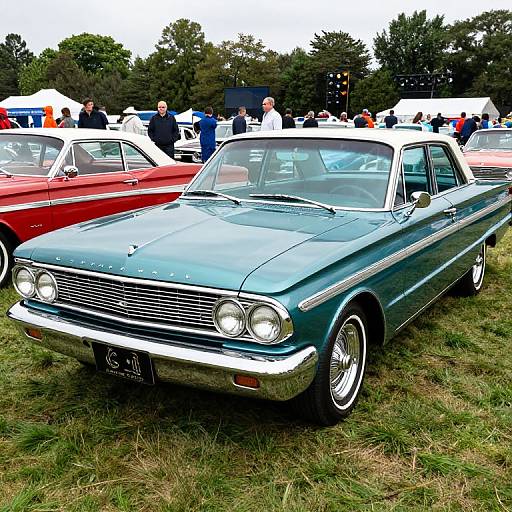 Photograph of a vintage, teal-green classic car with chrome details, parked on grass at a car show, surrounded by other classic cars and people in