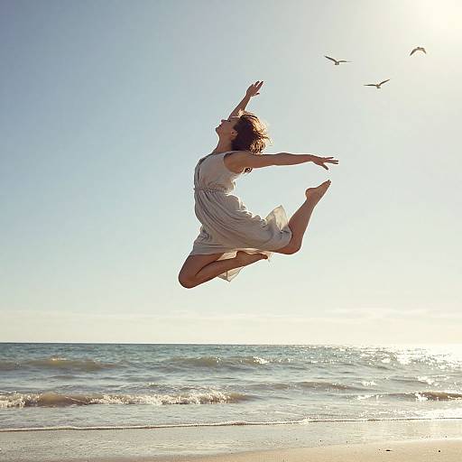 Photograph of a woman in a flowing white dress, mid-air jump, arms and legs spread, over a sunlit ocean with three birds flying in