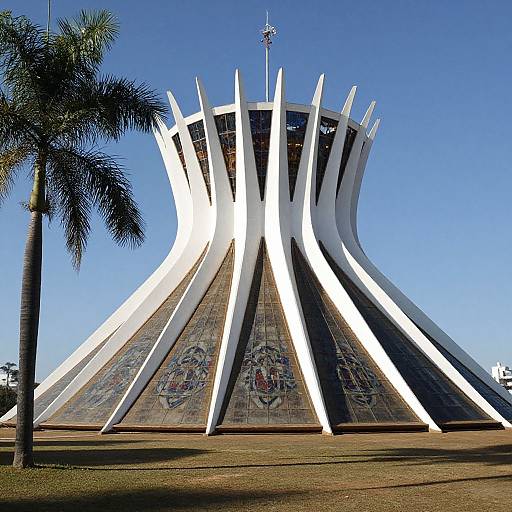 Photograph of a modern, white, spire-like building with sharp, angular lines, adorned with colorful graffiti, set against a clear blue sky,