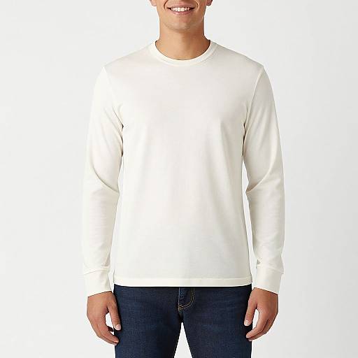 Photograph of a smiling man wearing a plain white long-sleeve shirt and dark blue jeans, standing against a white background.
