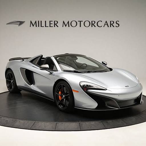 Photograph of a sleek, silver McLaren sports car with black accents and orange brake calipers, displayed on a circular platform against a white background with 