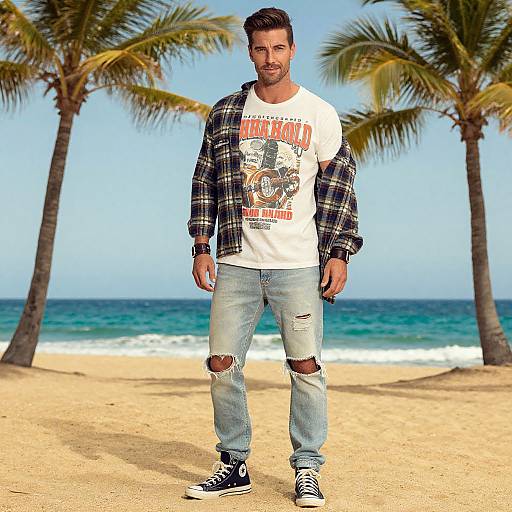 Photograph of a bearded man with dark hair, wearing a plaid shirt, white graphic tee, ripped jeans, and black sneakers, standing on