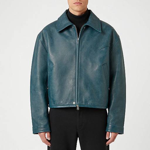 Photograph of a man in a teal leather jacket with a zipper, black turtleneck, and black pants, against a plain white background.